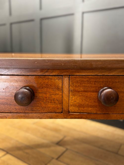 fig 4. A Victorian mahogany writing table featuring two front drawers with wooden turned knobs, four turned legs, and a drop-leaf panel.