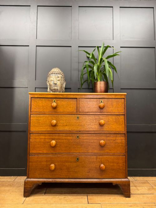 fig 1. An antique oak chest of drawers featuring two short drawers above three long graduating drawers, complete with turned wooden knobs and bracket feet.