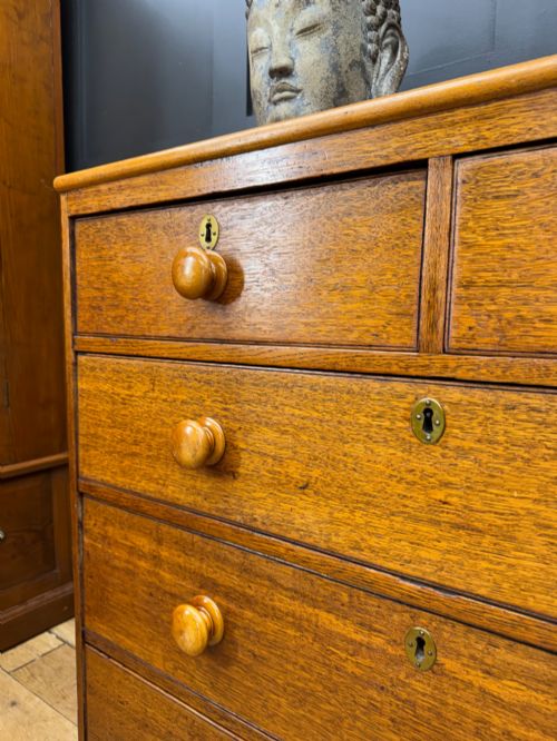 fig 3. An antique oak chest of drawers featuring two short drawers above three long graduating drawers, complete with turned wooden knobs and bracket feet.