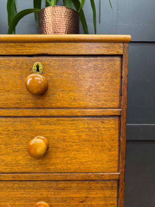 fig 4. An antique oak chest of drawers featuring two short drawers above three long graduating drawers, complete with turned wooden knobs and bracket feet.
