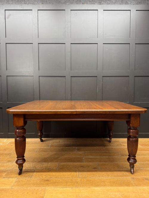 fig 1. A solid walnut Victorian extending dining table with reeded turned legs set on brass castors.