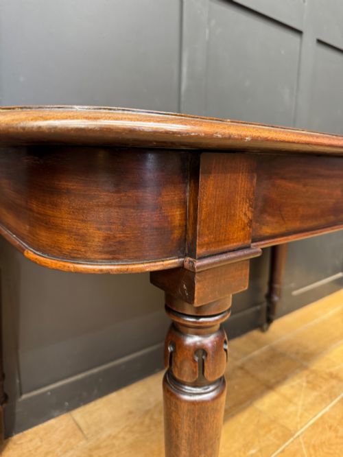 fig 4. A matching pair of dark mahogany side tables featuring turned legs and brass castors standing against a panelled wall.