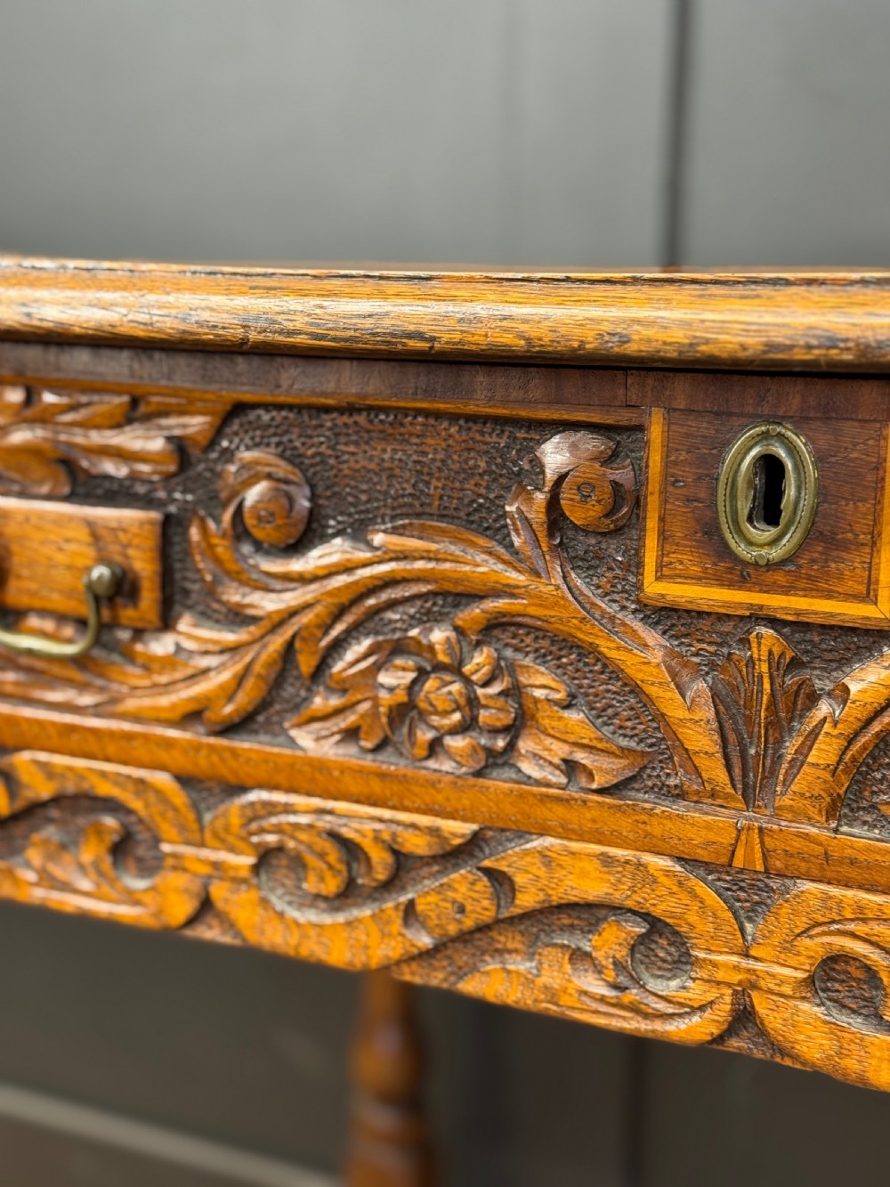 An antique carved oak side table featuring turned legs, a single carved drawer with brass handles, and lower stretchers. View IV