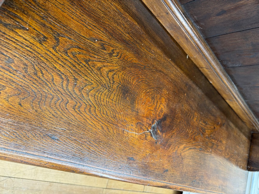An antique dark oak Welsh dresser featuring geometric moulded drawers, flanking upper cupboards, turned front legs, and an open plate rack. View II