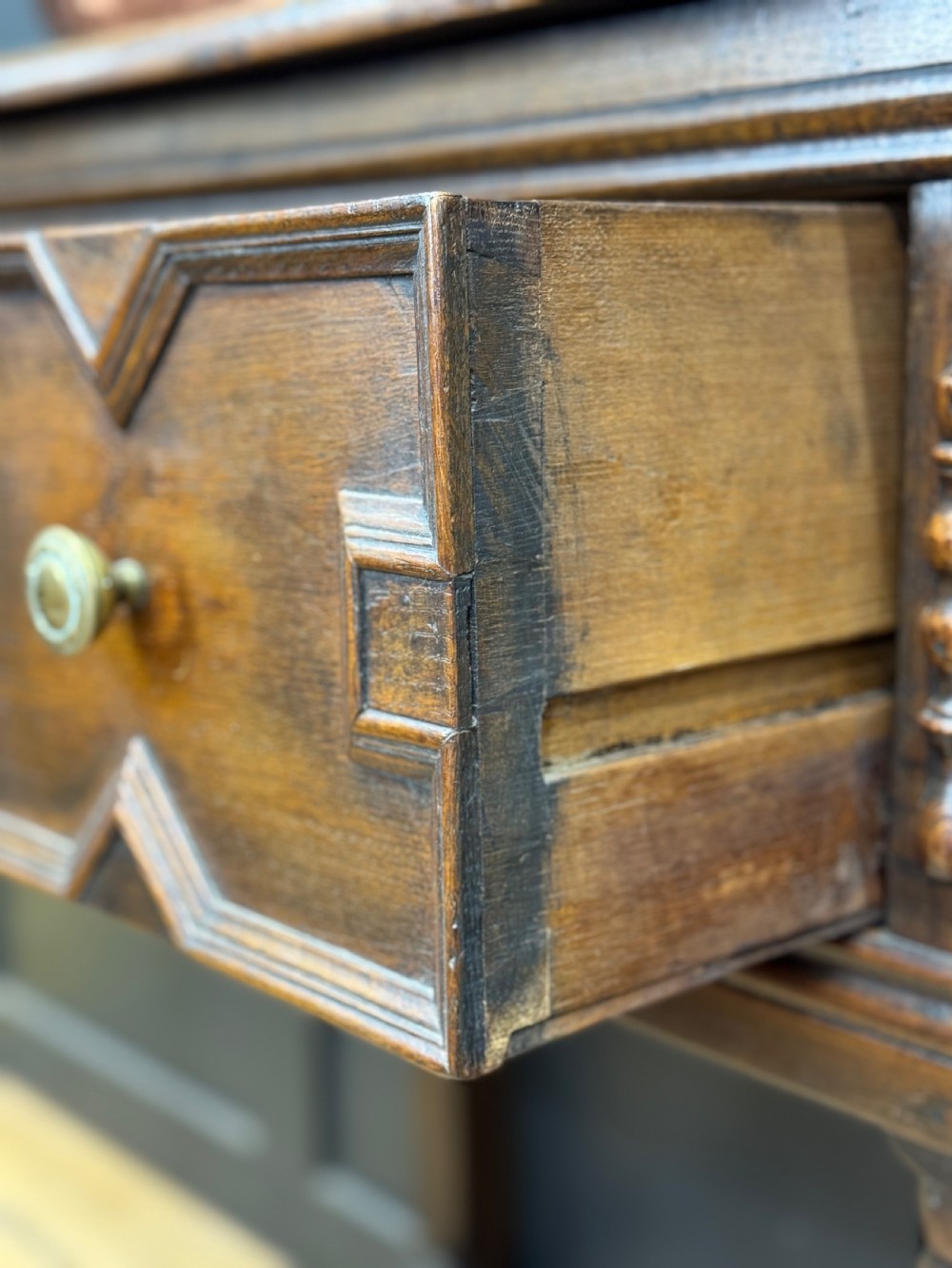 An antique dark oak Welsh dresser featuring geometric moulded drawers, flanking upper cupboards, turned front legs, and an open plate rack. View V