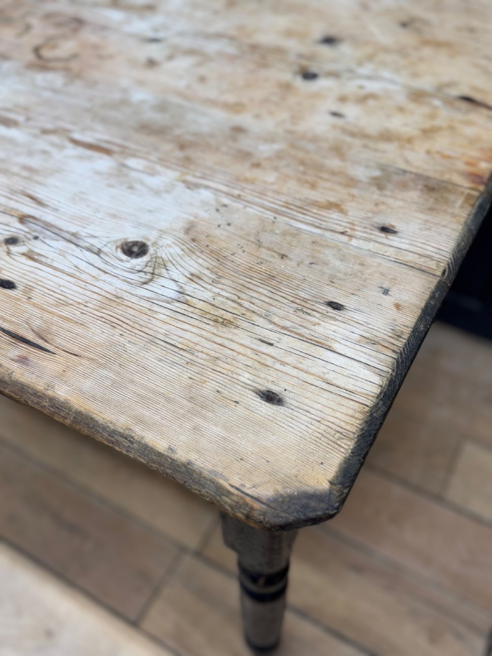 A Victorian pine kitchen table featuring a scrubbed natural wooden top and a distressed black painted frame with turned legs. View II
