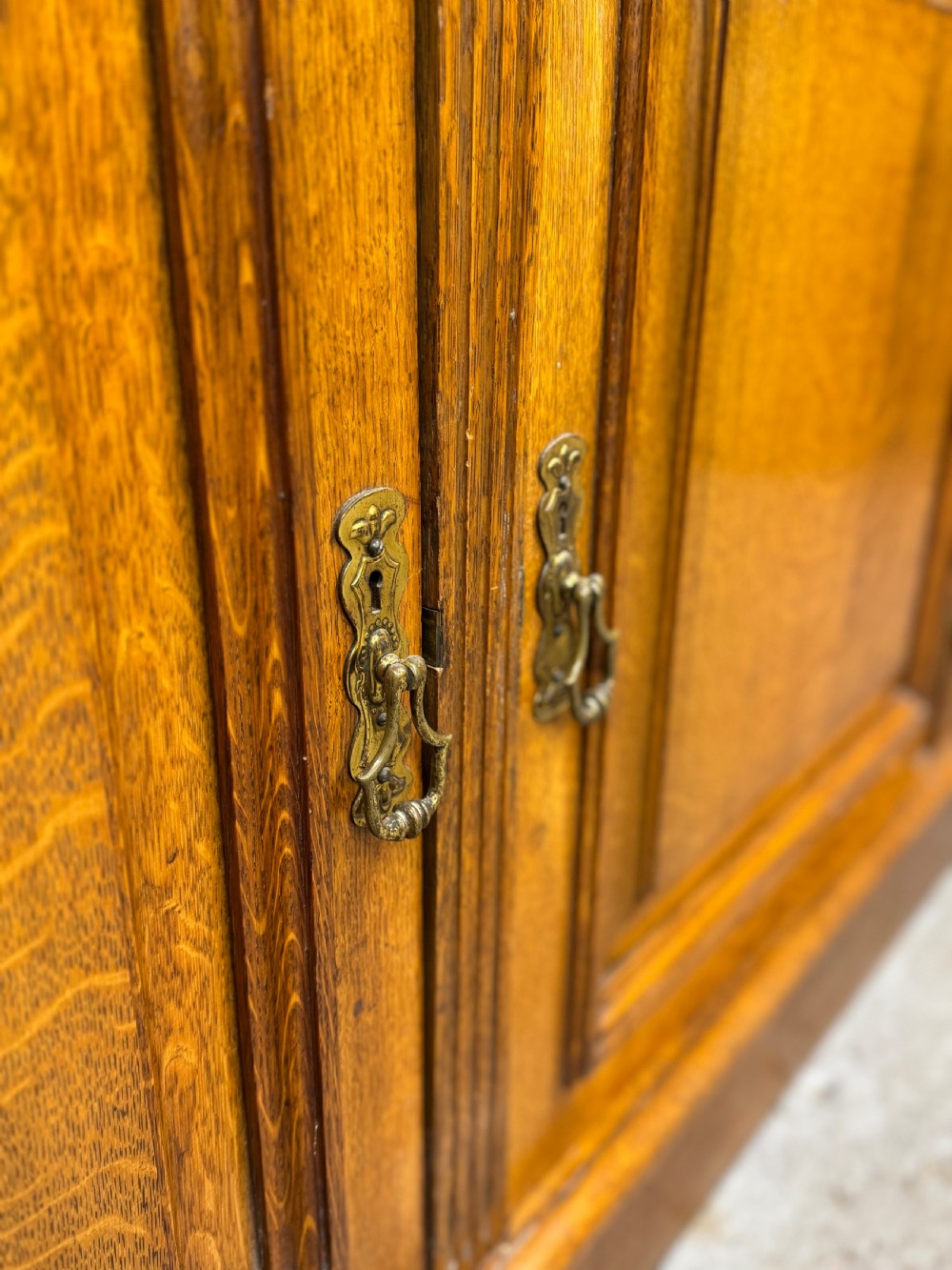 A large Victorian solid oak breakfront library bookcase with central panelled cupboard doors, drawers, open adjustable shelving, and carved corbels. View VIII
