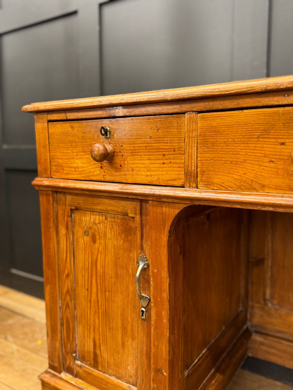 An antique pine pedestal desk featuring three top frieze drawers over two cupboard pedestals, resting on turned bun feet. View II