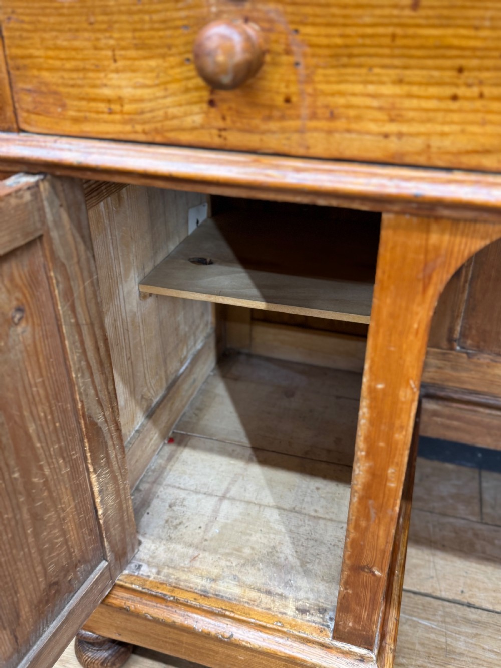 An antique pine pedestal desk featuring three top frieze drawers over two cupboard pedestals, resting on turned bun feet. View V