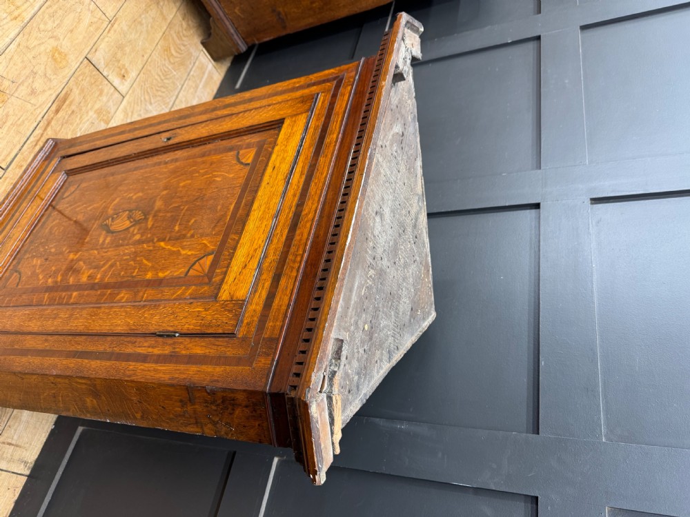 A Georgian oak wall corner cupboard featuring a single panel door with central shell marquetry inlay, crossbanded borders, and dentil moulding along the top cornice. View V