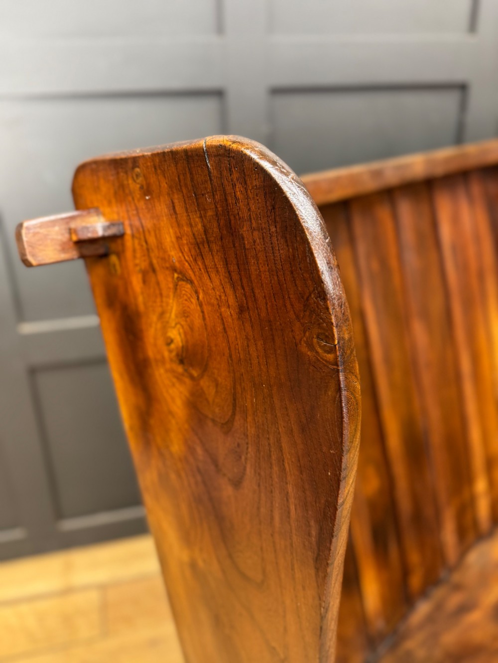 A curved antique elm wooden settle pew featuring a slatted high back, shaped side wings, and visible pegged joinery. View II