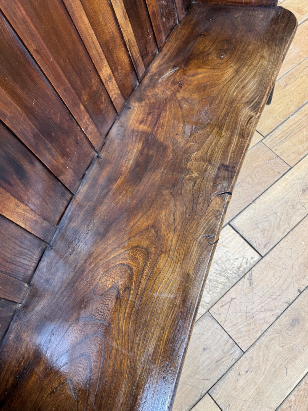 A curved antique elm wooden settle pew featuring a slatted high back, shaped side wings, and visible pegged joinery. View III