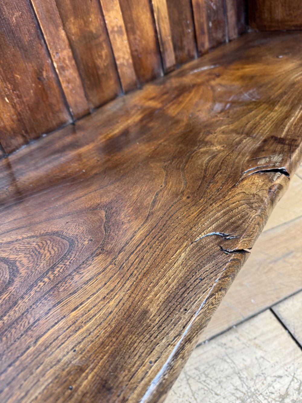 A curved antique elm wooden settle pew featuring a slatted high back, shaped side wings, and visible pegged joinery. View VI