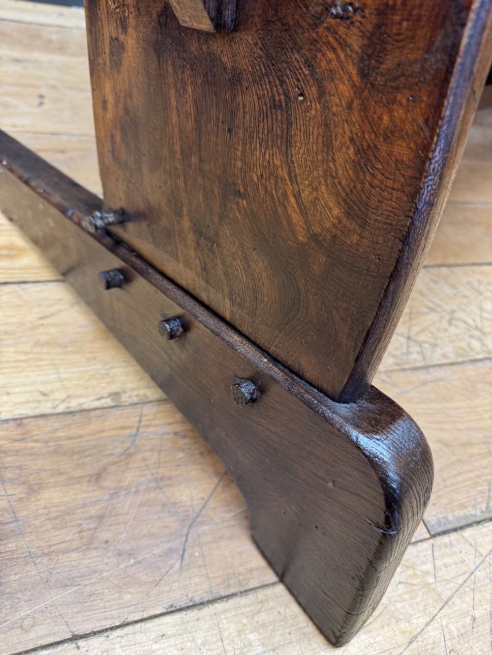 A curved antique elm wooden settle pew featuring a slatted high back, shaped side wings, and visible pegged joinery. View VII