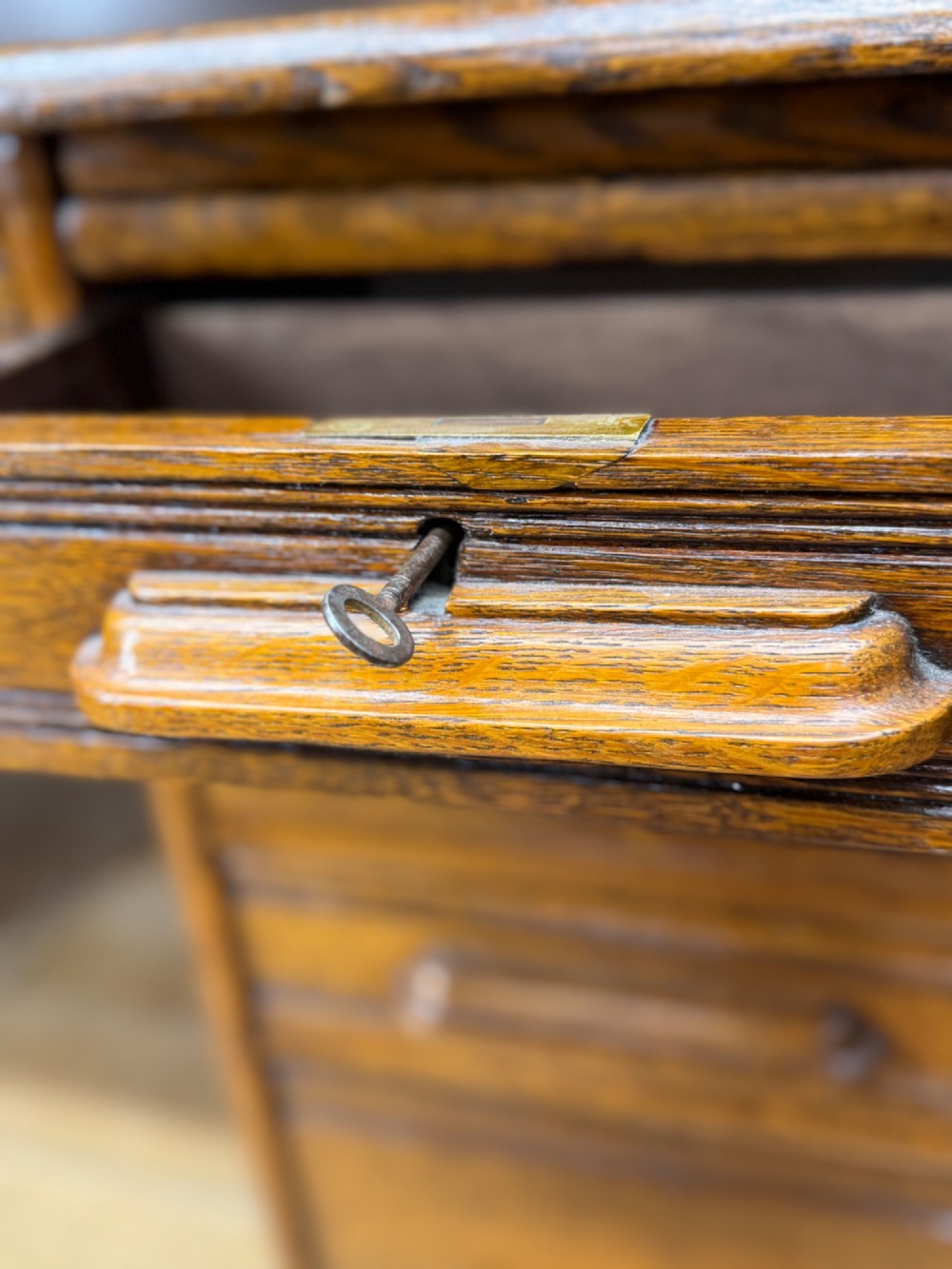 An Edwardian oak roll top pedestal desk featuring a flexible wooden tambour cover and twin drawer pedestals with carved handles. View IV