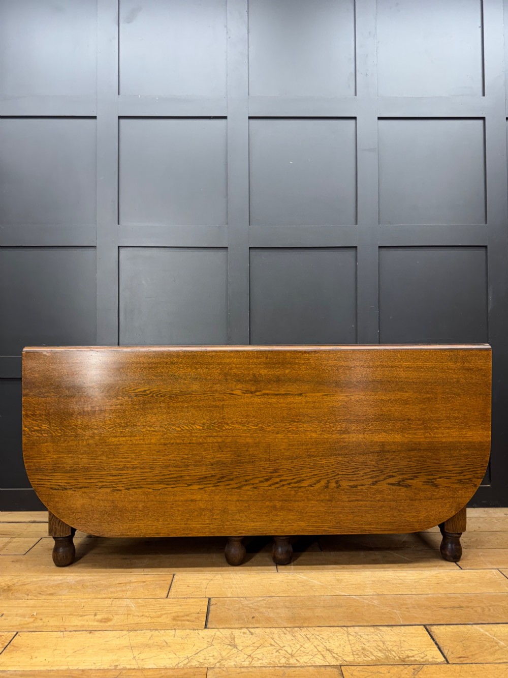 An Edwardian solid oak gateleg dining table with fully extended drop leaves, turned baluster legs, and lower stretchers. View II