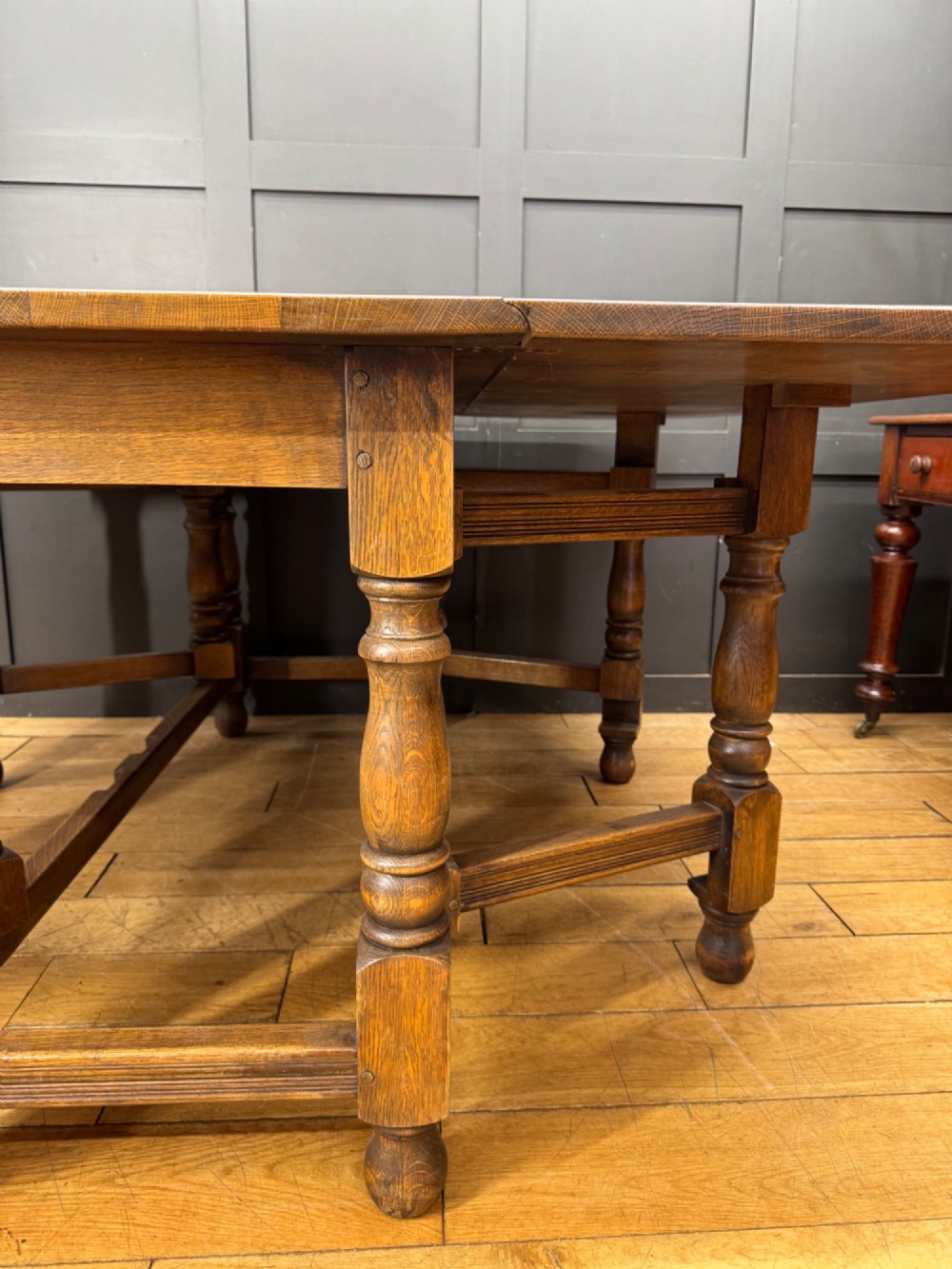 An Edwardian solid oak gateleg dining table with fully extended drop leaves, turned baluster legs, and lower stretchers. View V