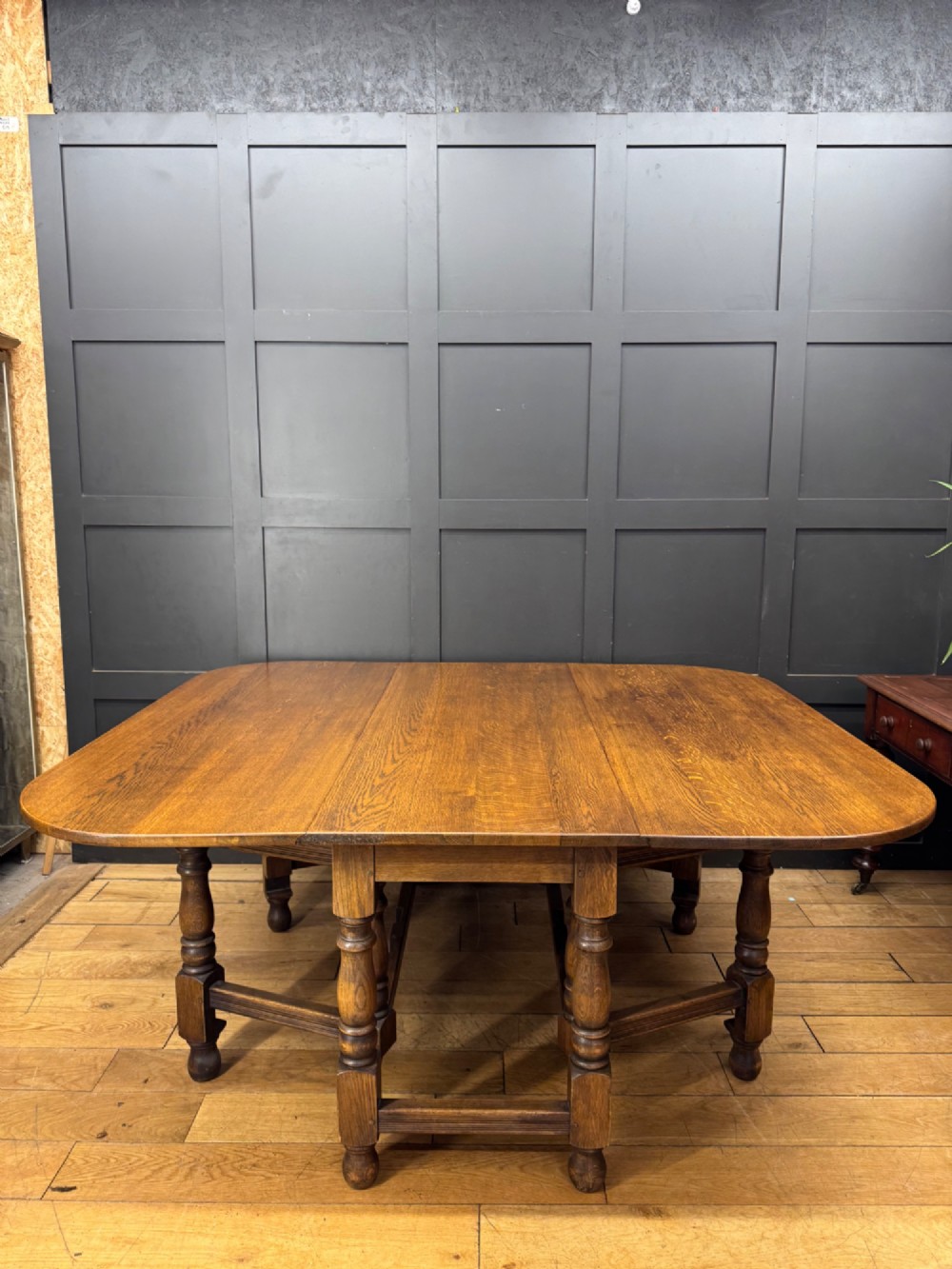 An Edwardian solid oak gateleg dining table with fully extended drop leaves, turned baluster legs, and lower stretchers. View VII