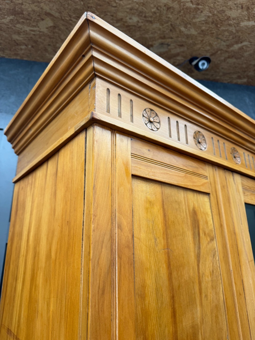 A tall Edwardian satinwood wardrobe featuring a central mirrored door, panelled side doors, a carved rosette frieze, and a wide drawer at the base. View II