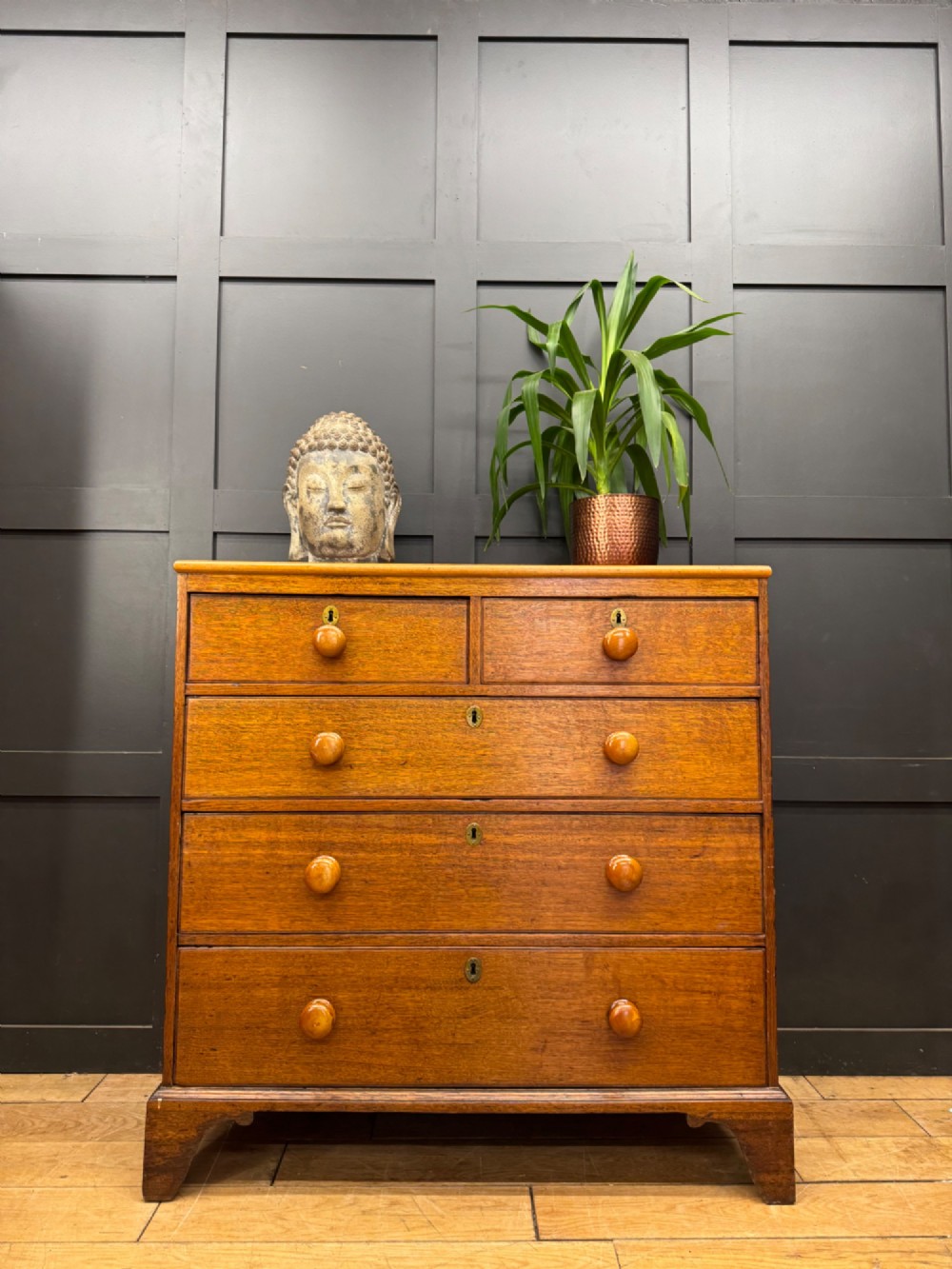 An antique oak chest of drawers featuring two short drawers above three long graduating drawers, complete with turned wooden knobs and bracket feet. View II