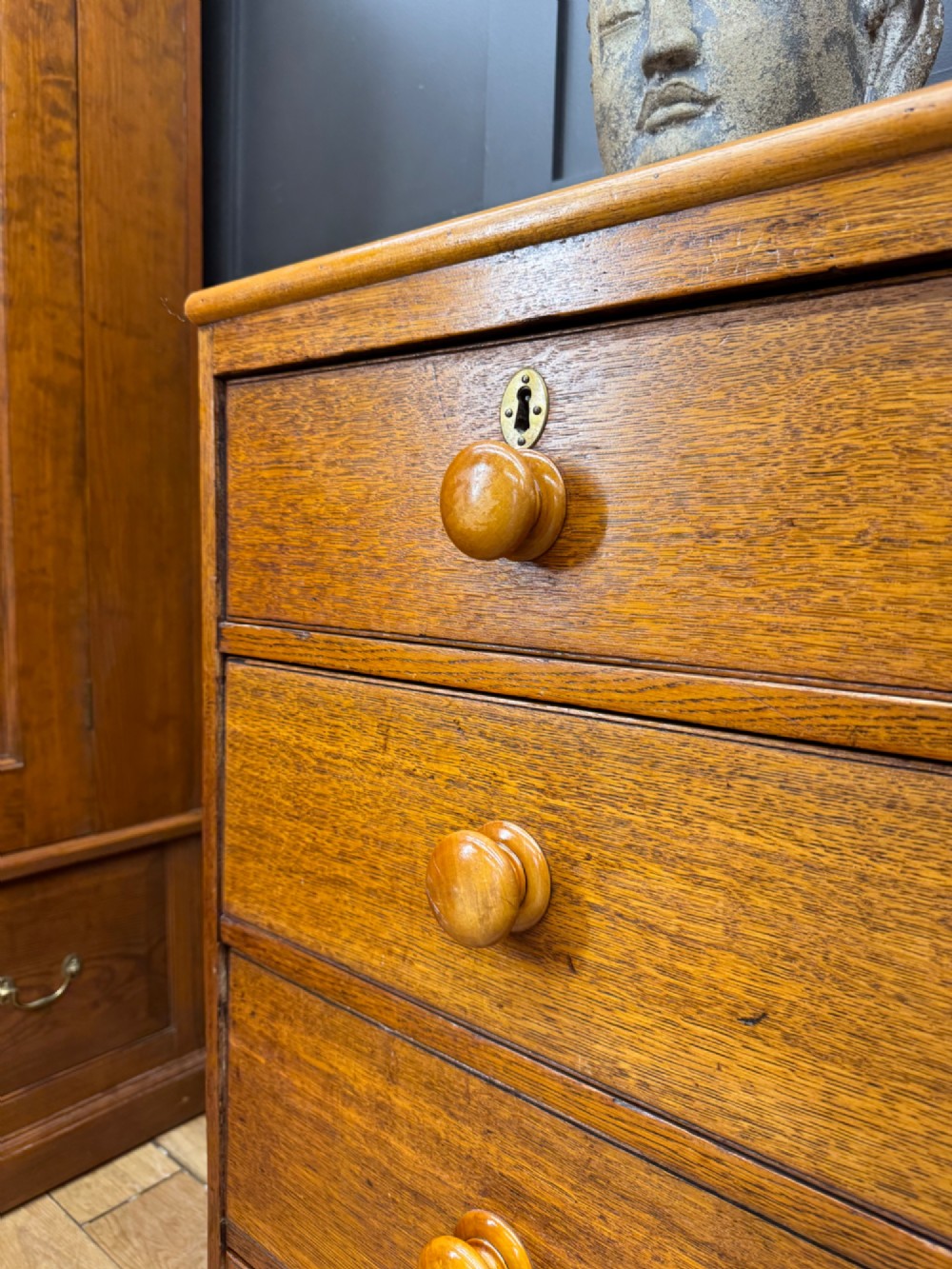 An antique oak chest of drawers featuring two short drawers above three long graduating drawers, complete with turned wooden knobs and bracket feet. View III