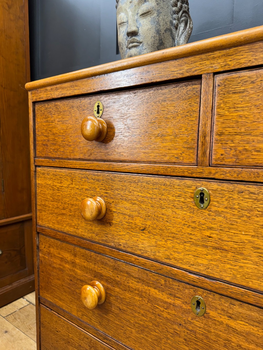 An antique oak chest of drawers featuring two short drawers above three long graduating drawers, complete with turned wooden knobs and bracket feet. View IV