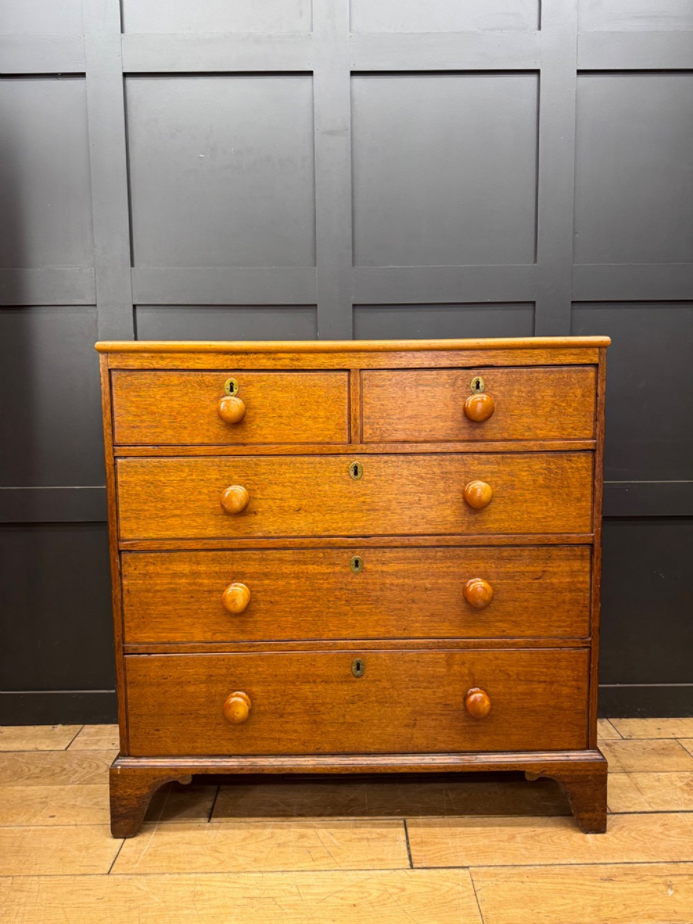 An antique oak chest of drawers featuring two short drawers above three long graduating drawers, complete with turned wooden knobs and bracket feet. View VIII