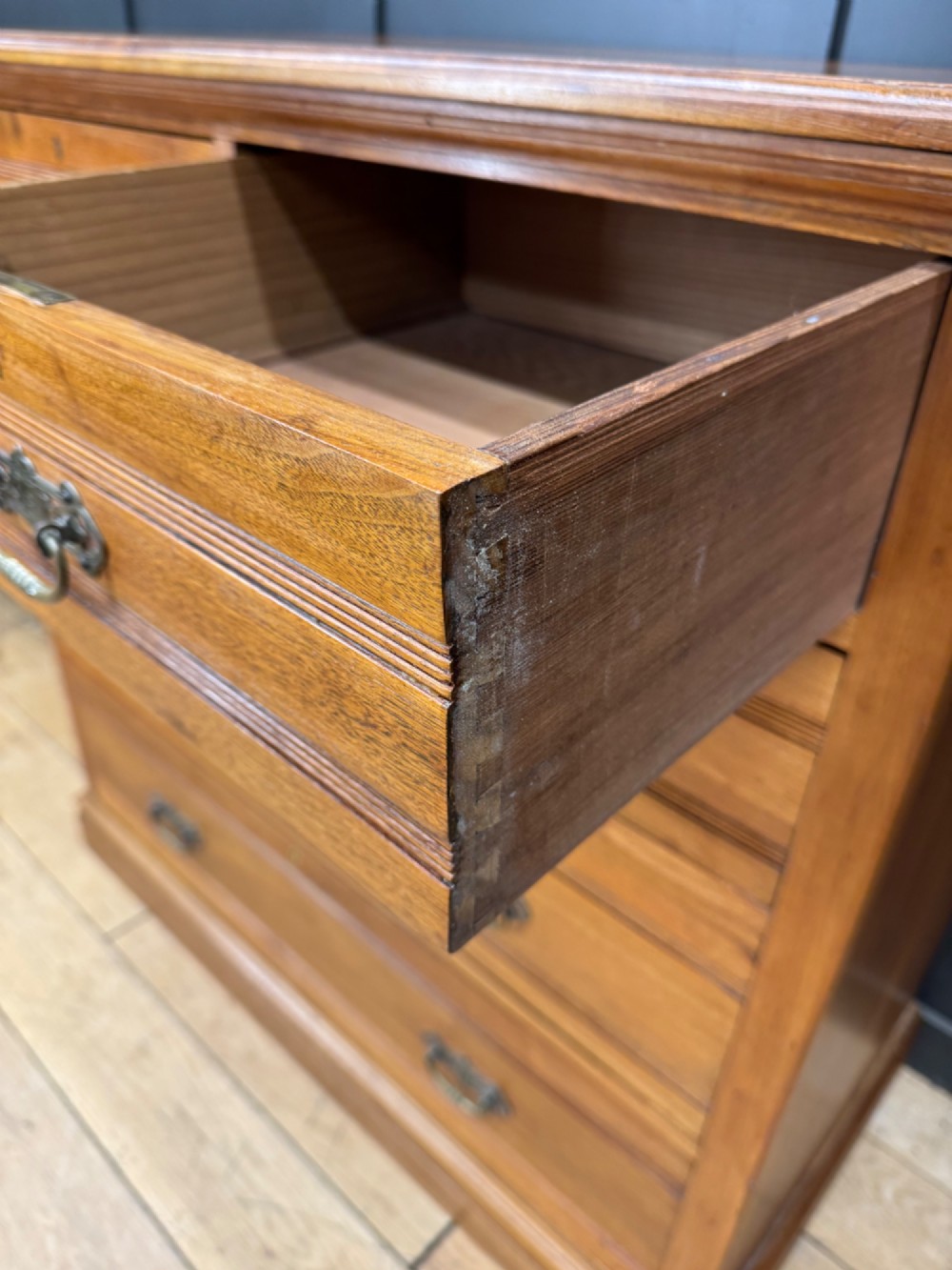 A Victorian antique walnut chest featuring two short over three long drawers with ornate brass handles and reeded drawer fronts resting on a solid plinth base. View III