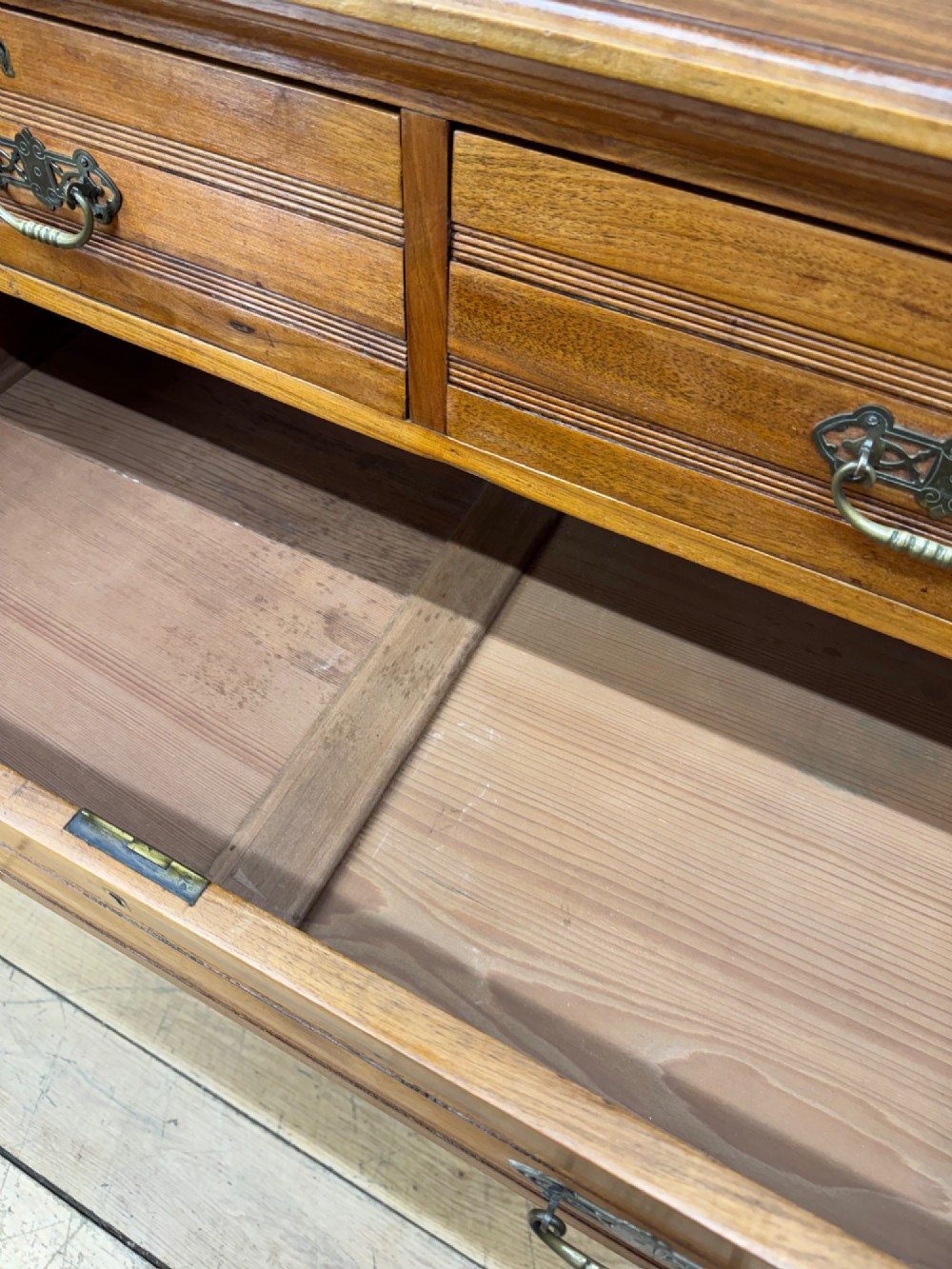 A Victorian antique walnut chest featuring two short over three long drawers with ornate brass handles and reeded drawer fronts resting on a solid plinth base. View V
