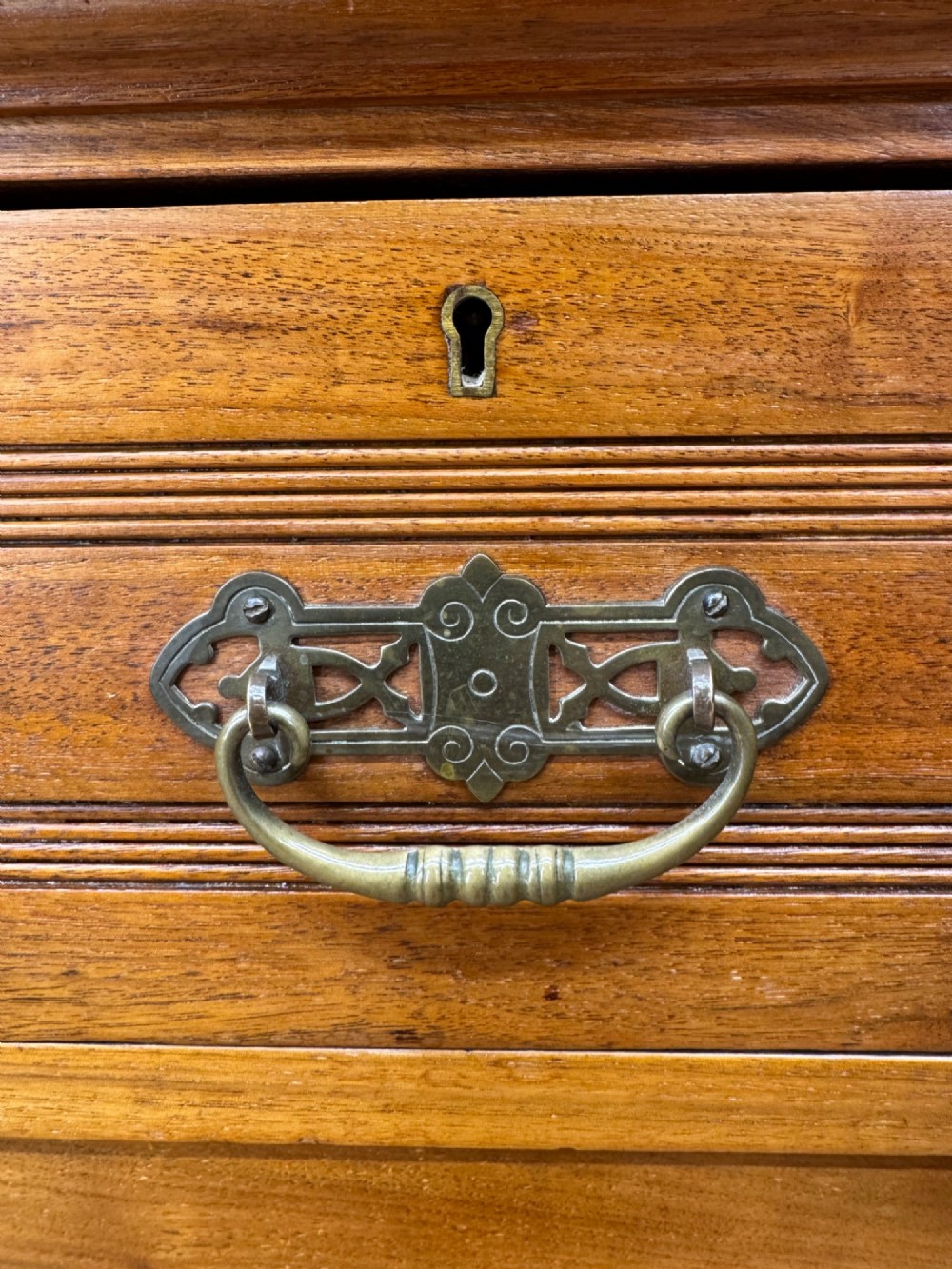 A Victorian antique walnut chest featuring two short over three long drawers with ornate brass handles and reeded drawer fronts resting on a solid plinth base. View IX