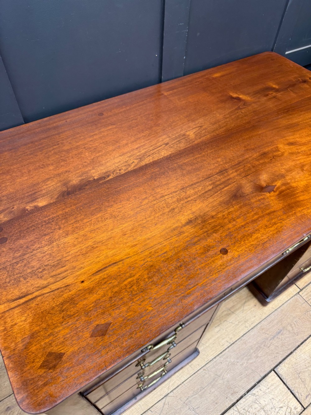 An antique mahogany pedestal desk featuring three frieze drawers, twin drawer pedestals with brass drop handles, and a solid plinth base. View VI