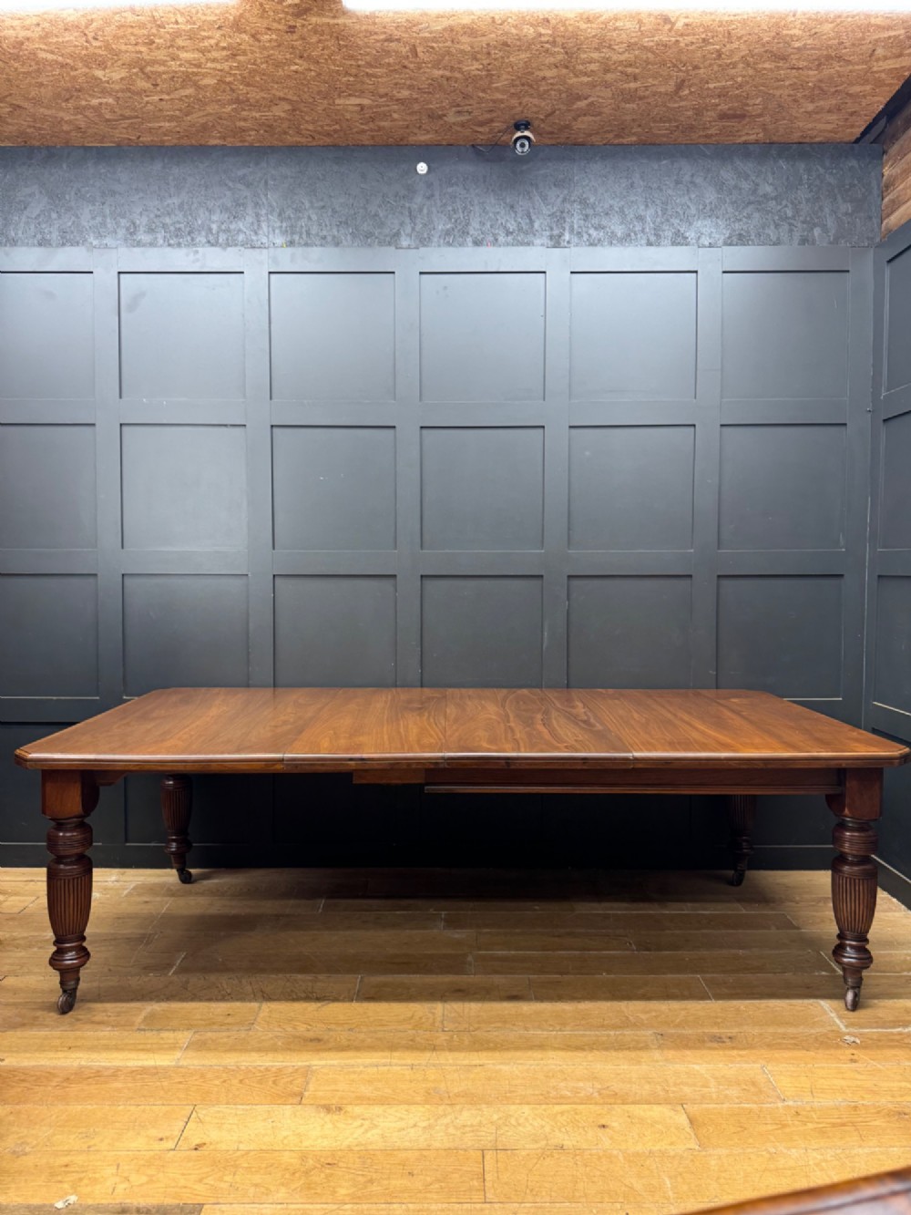 A solid walnut Victorian extending dining table with reeded turned legs set on brass castors.