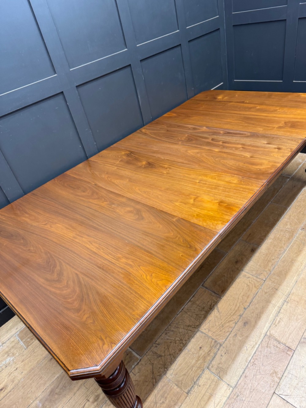 A solid walnut Victorian extending dining table with reeded turned legs set on brass castors. View VII