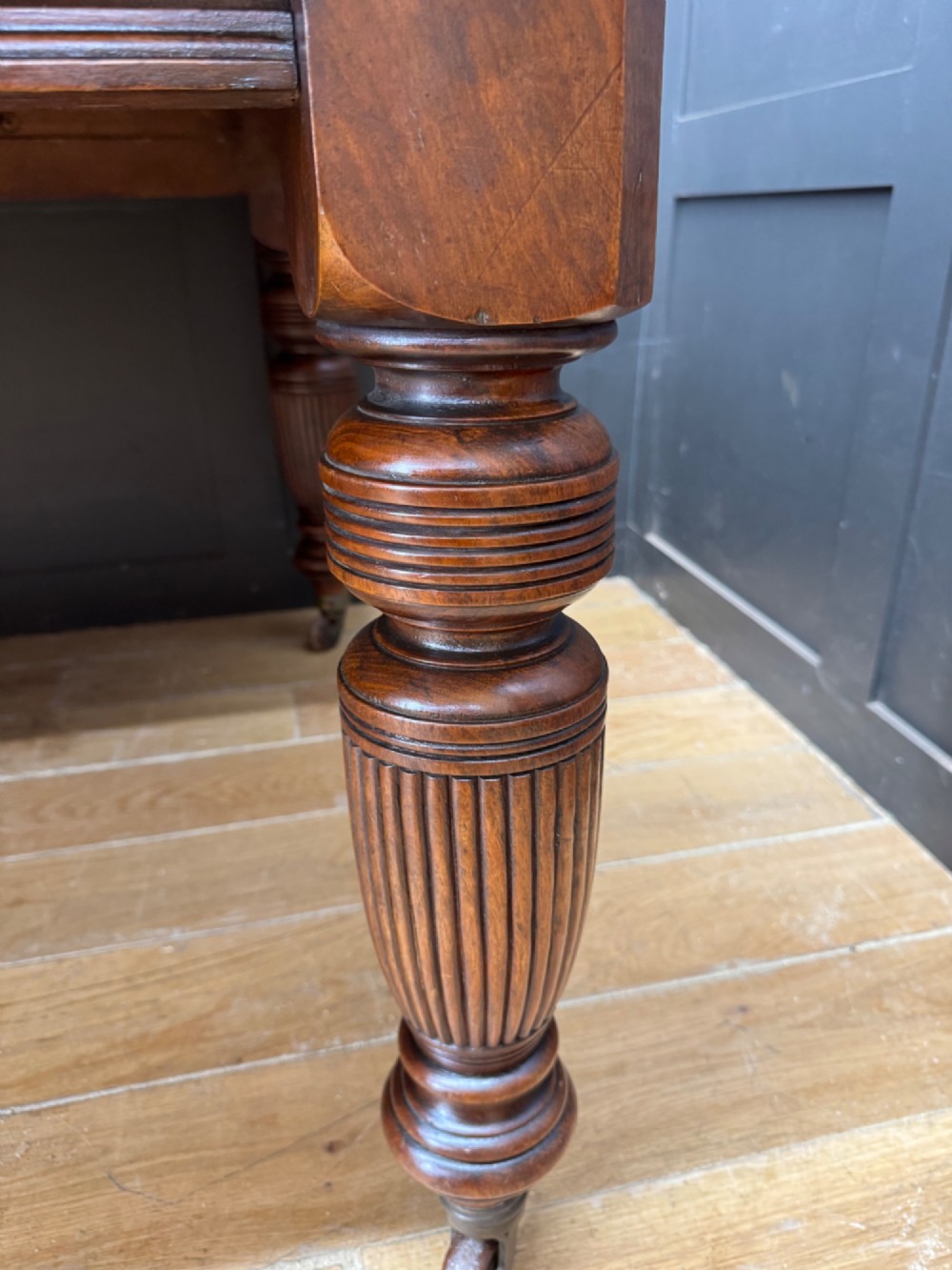 A solid walnut Victorian extending dining table with reeded turned legs set on brass castors. View IX