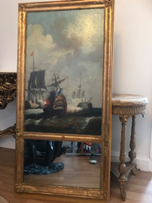 fig 1. A tall rectangular French trumeau mirror with a gilded frame containing an upper oil painting of a naval seascape and a lower mirror glass section.
