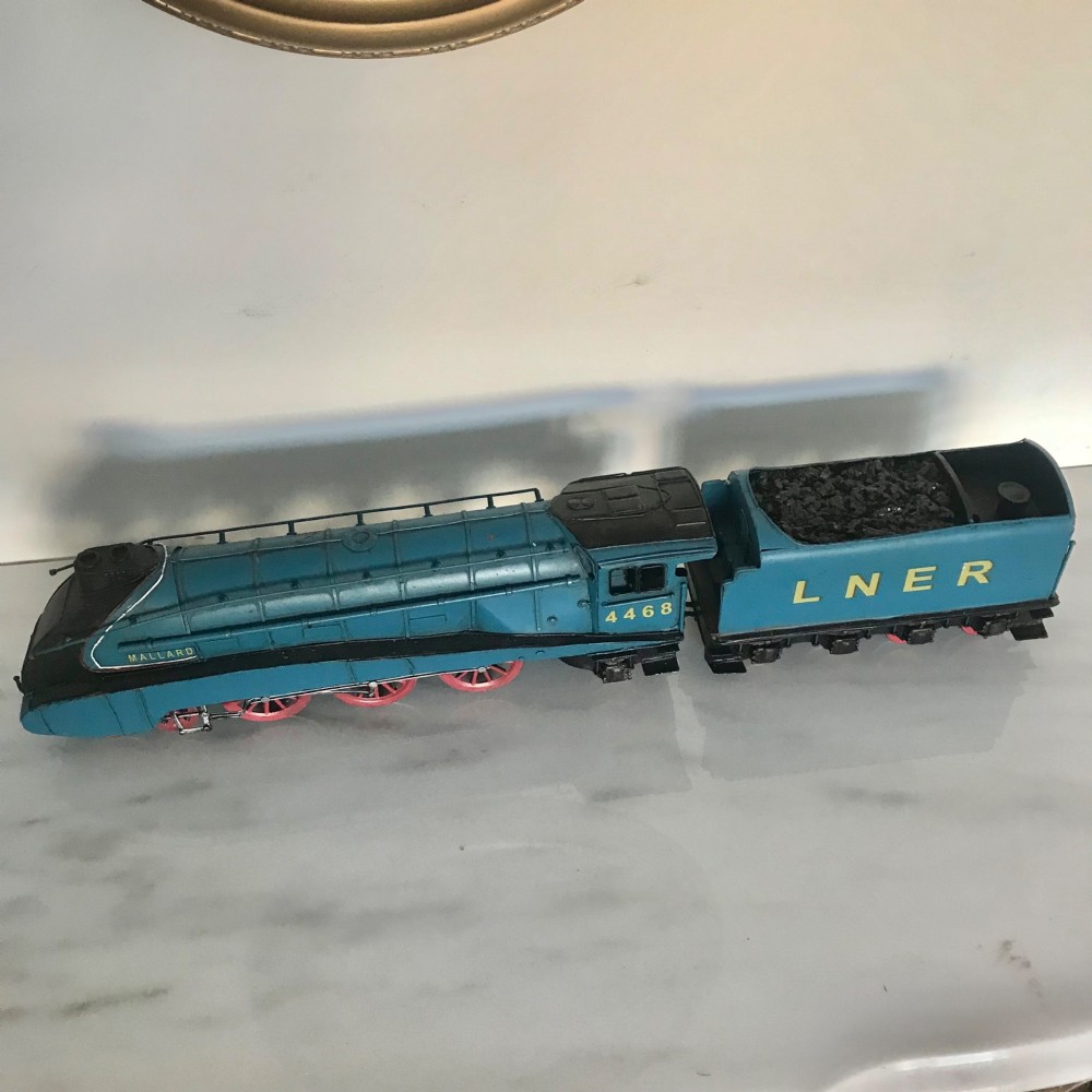 A garter blue LNER Class A4 Mallard O gauge model steam locomotive and matching coal tender with yellow lettering and red spoked wheels.