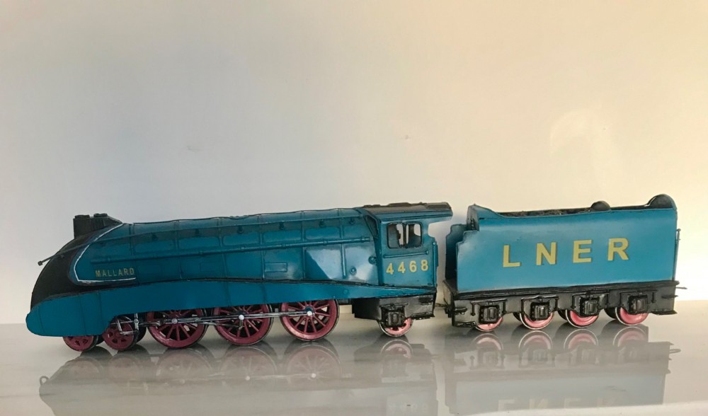 A garter blue LNER Class A4 Mallard O gauge model steam locomotive and matching coal tender with yellow lettering and red spoked wheels. View II