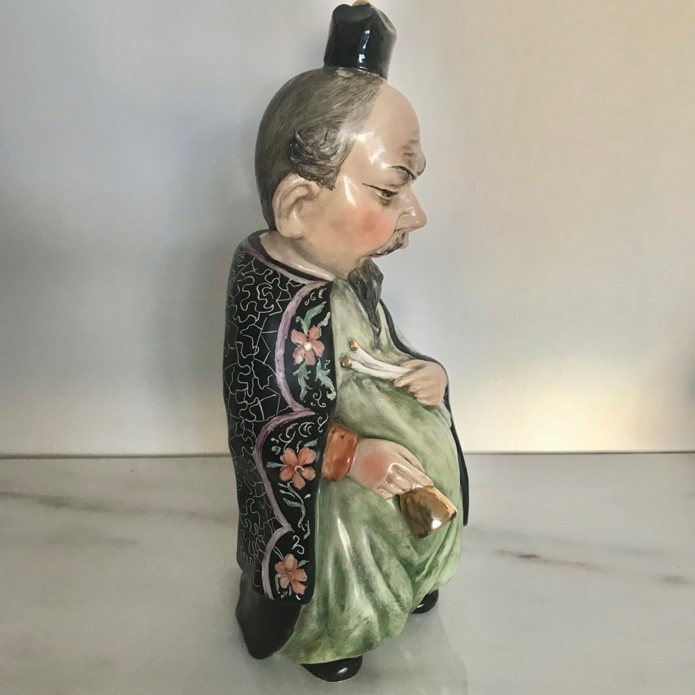A Chinese ceramic figurine of a scholar wearing a black patterned robe and green garments, holding two scrolls and a small gold bell. View VII