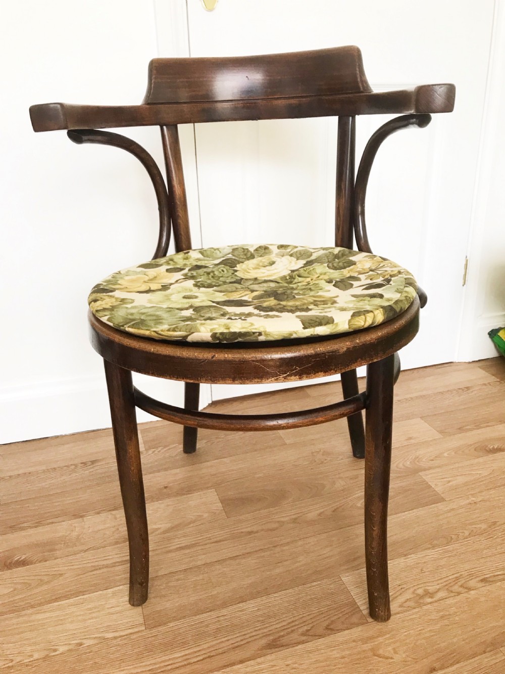 A dark brown stained bentwood carver chair featuring curved armrests, turned front legs, and an embossed circular wooden seat panel. View VI