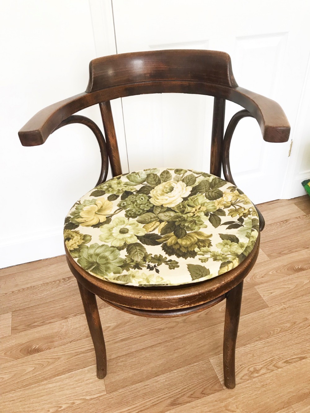 A dark brown stained bentwood carver chair featuring curved armrests, turned front legs, and an embossed circular wooden seat panel. View VII
