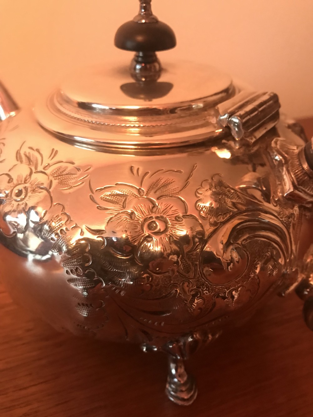 An Edwardian three-piece silver-plated tea set comprising a teapot, milk jug, and sugar bowl featuring floral chasing and scroll feet. View XVII