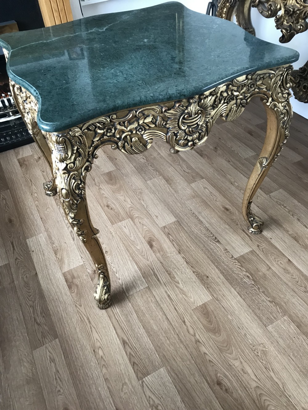 A French Rococo Revival style occasional table with a serpentine green marble top supported by an ornate gilded frame with carved cabriole legs. View XXVI