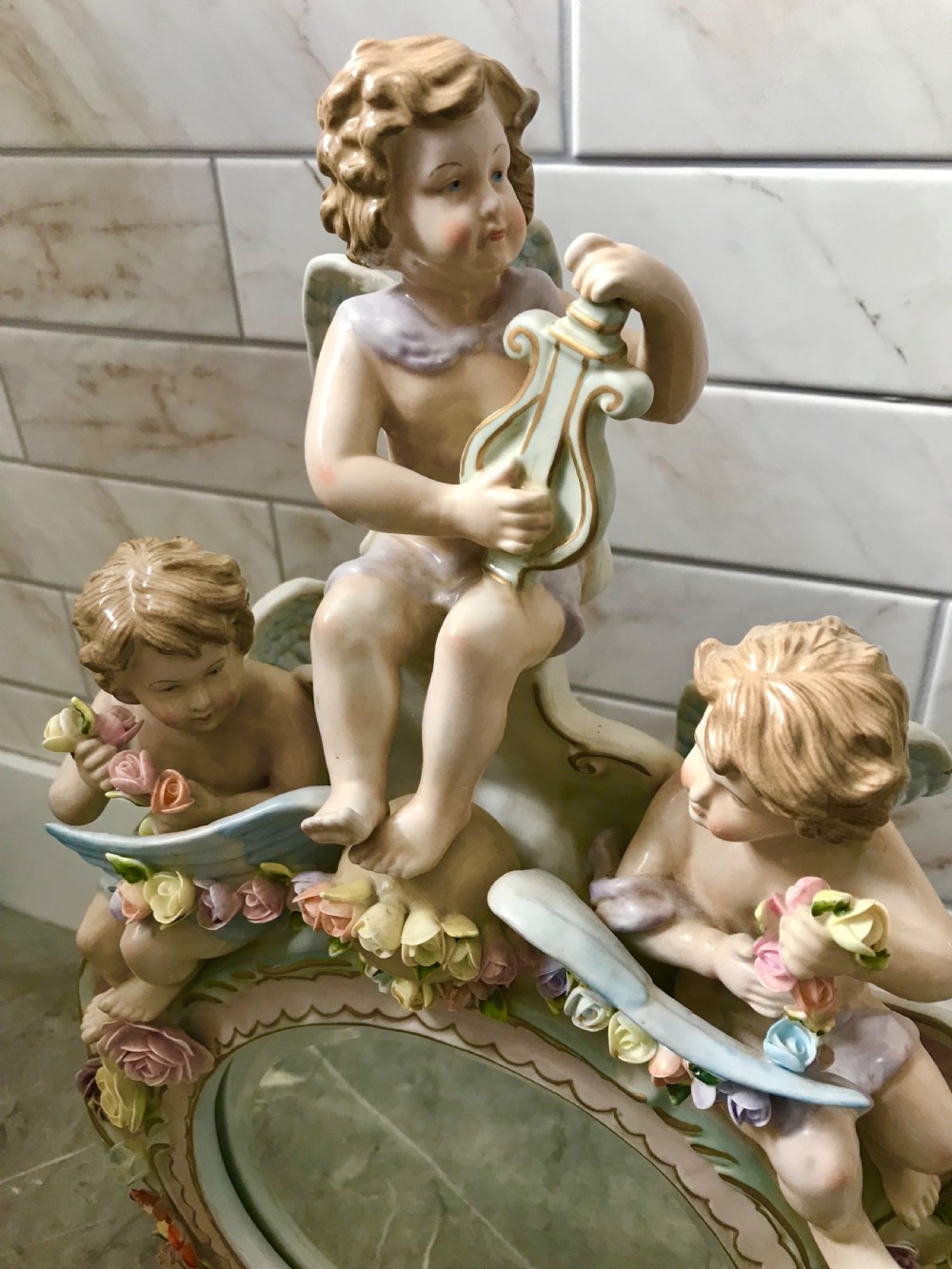 An ornate Continental porcelain table mirror featuring sculpted winged cherubs and hand-modelled floral encrustations around a circular mirror frame. View XVI