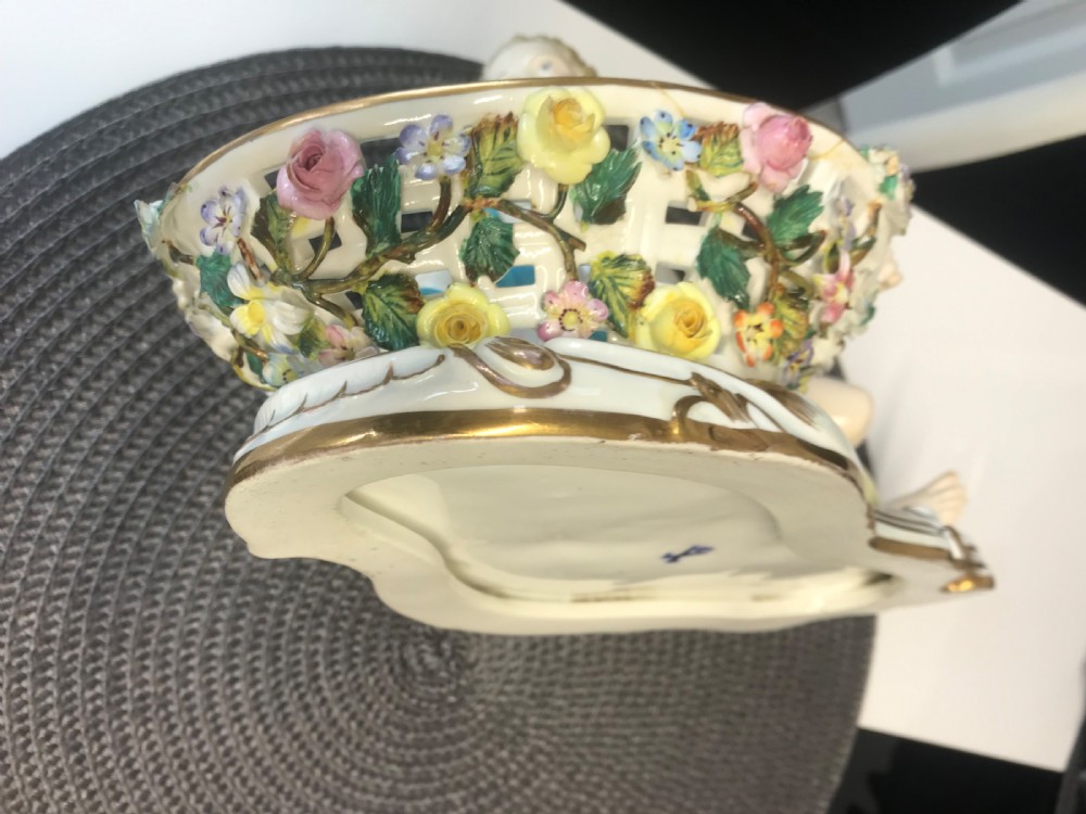 An 18th-century porcelain sweetmeat dish featuring a reclining female figure beside an openwork lattice basket adorned with hand-painted polychrome flowers and gilt trim. View XIV