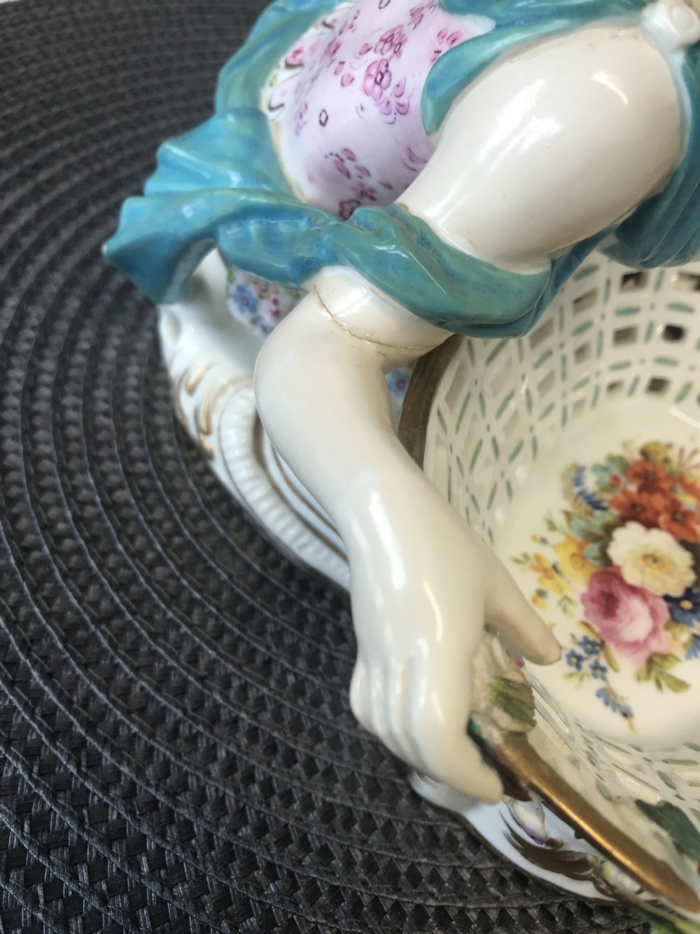 An 18th-century porcelain sweetmeat dish featuring a reclining female figure beside an openwork lattice basket adorned with hand-painted polychrome flowers and gilt trim. View XIX