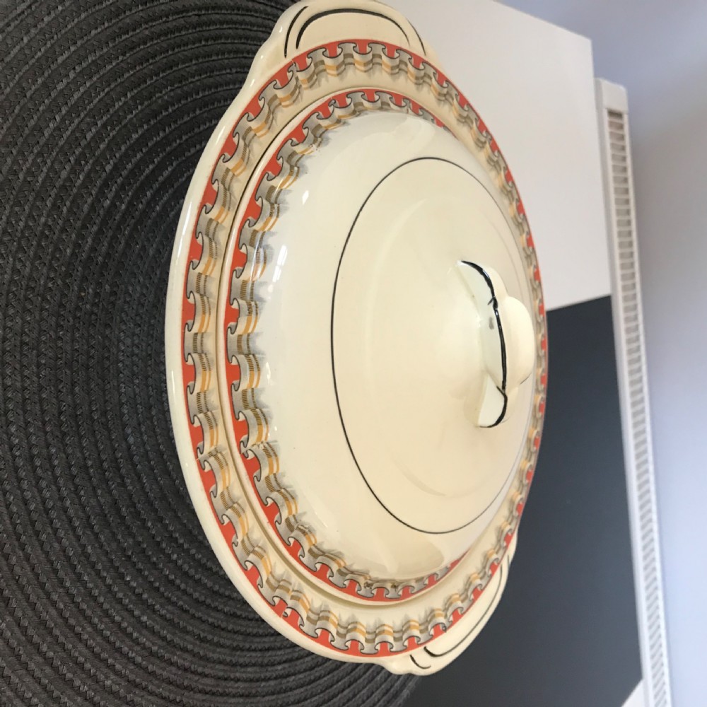 An Art Deco cream earthenware lidded vegetable tureen featuring a geometric pattern in orange and grey along the rim. View X