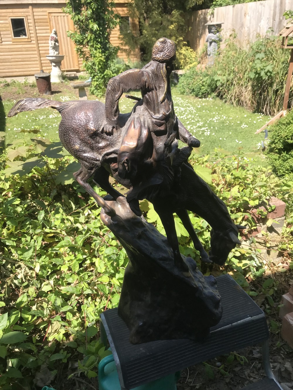 A dark brown bronze sculpture of a horse and rider descending a steep rocky slope after a design by Frederic Remington. View VI