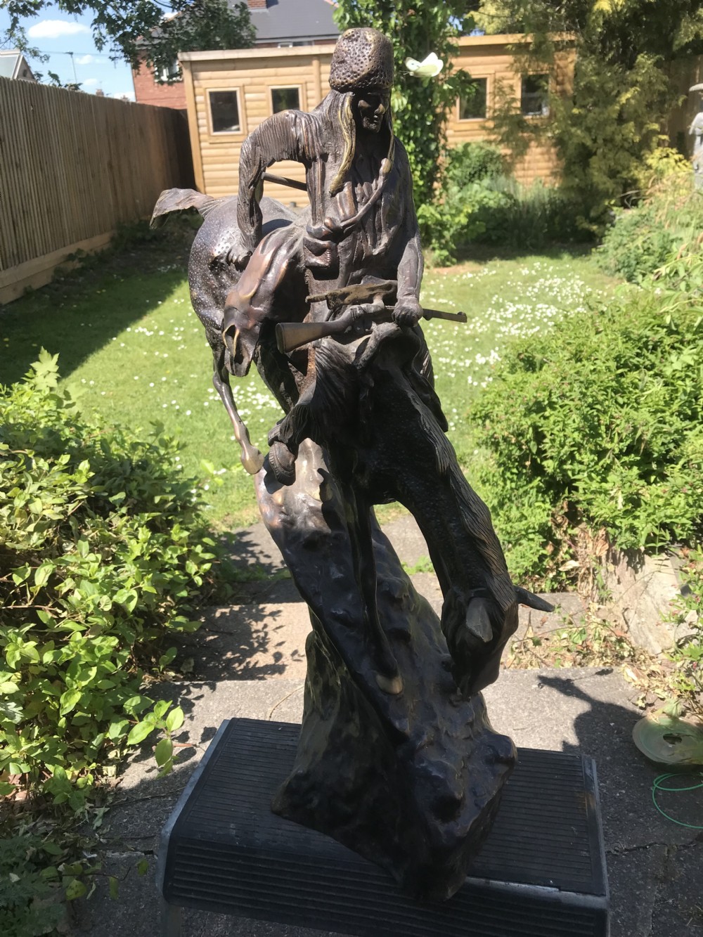 A dark brown bronze sculpture of a horse and rider descending a steep rocky slope after a design by Frederic Remington. View VII