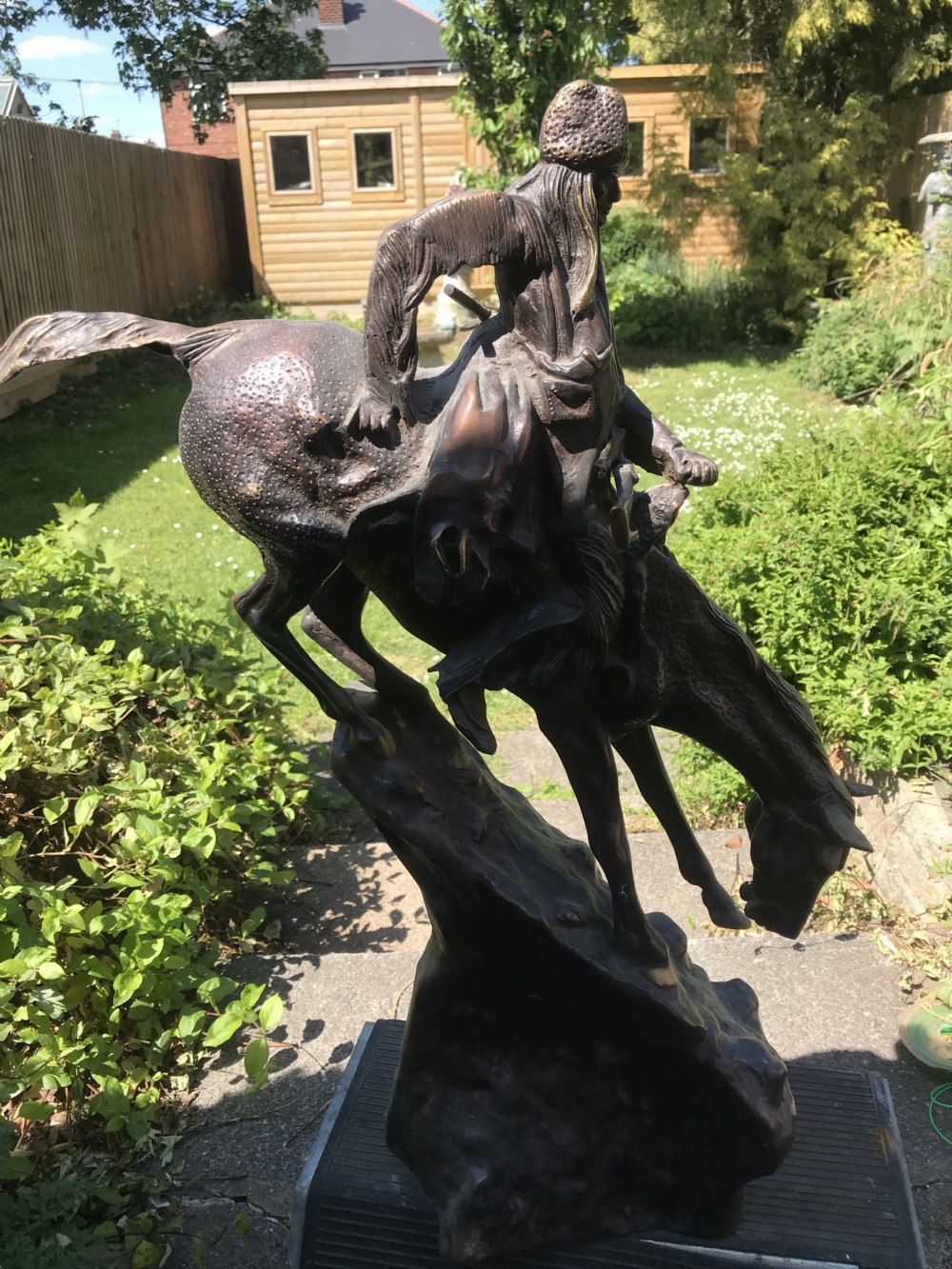 A dark brown bronze sculpture of a horse and rider descending a steep rocky slope after a design by Frederic Remington. View IX