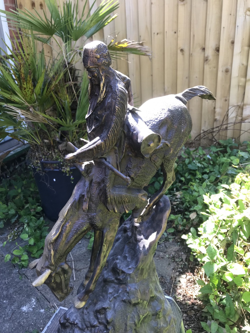 A dark brown bronze sculpture of a horse and rider descending a steep rocky slope after a design by Frederic Remington. View XI
